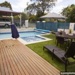 jade swimming pool design with sandstone paving and decking