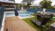 jade swimming pool design with sandstone paving and decking
