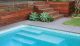 Corner of a pool with wooden stairs and succulent plants