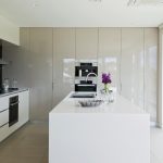 A simple modern kitchen with a white island and bright flowers