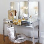 A three-mirror silver dressing table adds a luxe metallic feel to a crisp white bedroom
