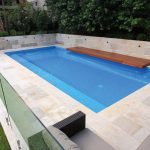 Blue pool with brown wooden bench and a blue waterslide