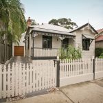 The traditional exterior of the home is juxtaposed by the stone driveway