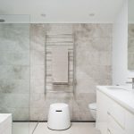 A tiled feature wall evokes depth in a white bathroom