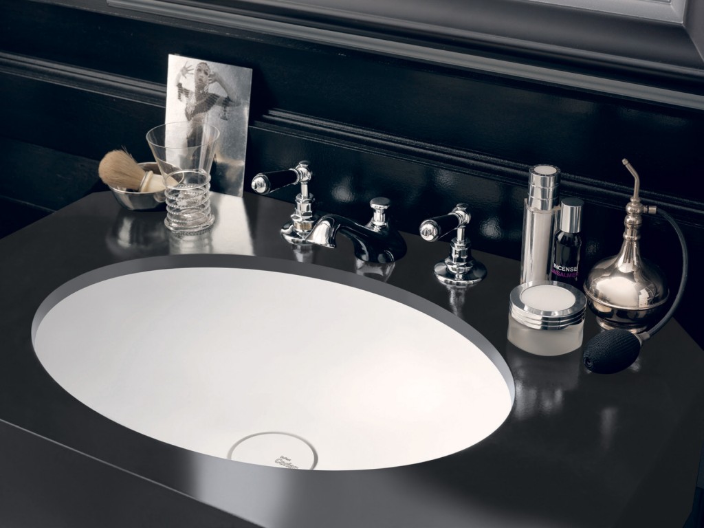 Integrated into a jet-black mount made from Corian Deep Nocturne, the sleek Corian Relax washbasin works in crisp contrast with the dark wall panelling and chequerboard tiled floor to evoke a timeless elegance.