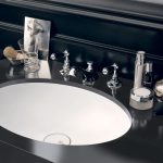 Integrated into a jet-black mount made from Corian Deep Nocturne, the sleek Corian Relax washbasin works in crisp contrast with the dark wall panelling and chequerboard tiled floor to evoke a timeless elegance.