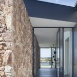 A natural stone wall adds a rustic element to the home’s interior and exterior