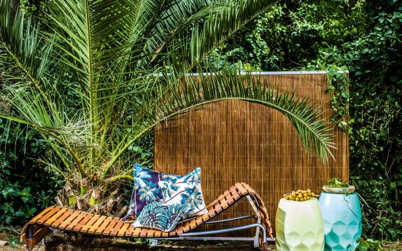 Adjustable day bed  and multi-function screen  in Natural. Designed  by Mark Snyders.  houseofbamboo.com.au Hex tables in Minty  Powder Blue and Pale Yellow, Oasis outdoor cushion in Palm Trees  and South Pacific.  escapetoparadise.com.au