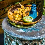 Large Resin Earth bowl in Dark Horn, Resin Boulder salt grinder in Moody Blue, Resin Cloud dish and side plate in Seaweed Malachite, Cloud bowl in brass and Resin Modern Tribal platter in Emerald Swirl. dinosaurdesigns.com.au Bambileke stool/side table and decorative metal screen. yardware.com.au