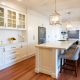 A stylish family style kitchen - wide shot of a spacious white kitchen decorated with fruit and hanging lights