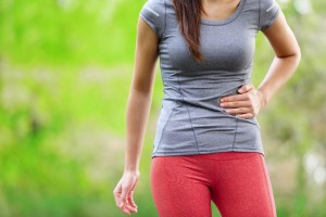 woman runner holding her stomach in pain