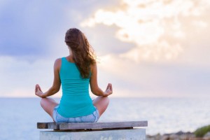 woman meditating facing the ocean