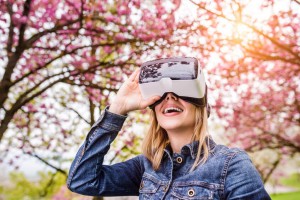 Blond woman wearing virtual reality goggles outside in spring nature