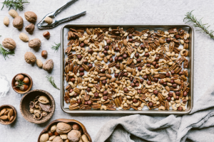 a few cups of mixed nuts are placed on a rimmed baking sheet to be toasted in the oven.