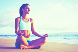 Happy young woman practicing yoga on the beach at sunset. Health