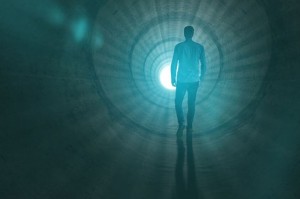 Man walking to the light at the end of the tunnel