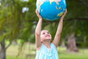 little girl holding a globe on a sunny day