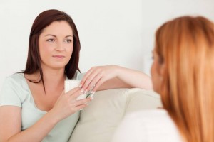 Chatting Women sitting on a sofa with cups in a living room