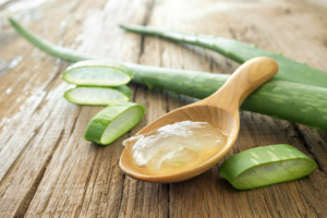 aloe vera gel on wooden spoon with aloe vera on wooden table