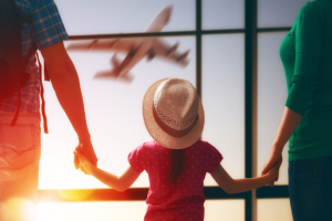 happy family with child at the airport. parents and child girl look out the window at the airplane.