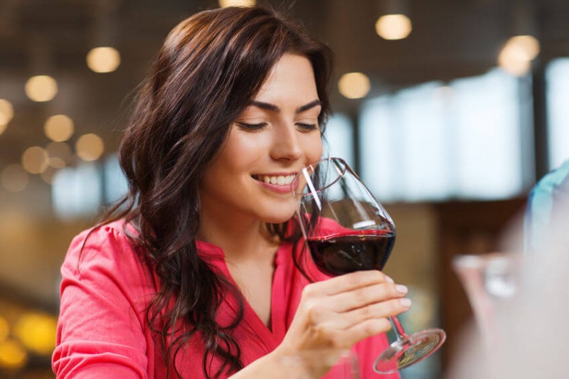 woman smiling with a glass of red wine in hand