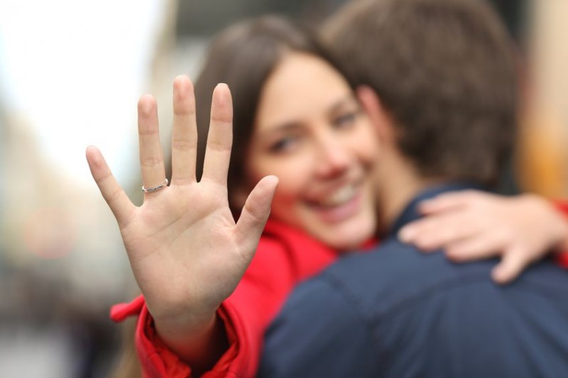 woman looking at her engagement ring on her finger while hugging her boyfriend